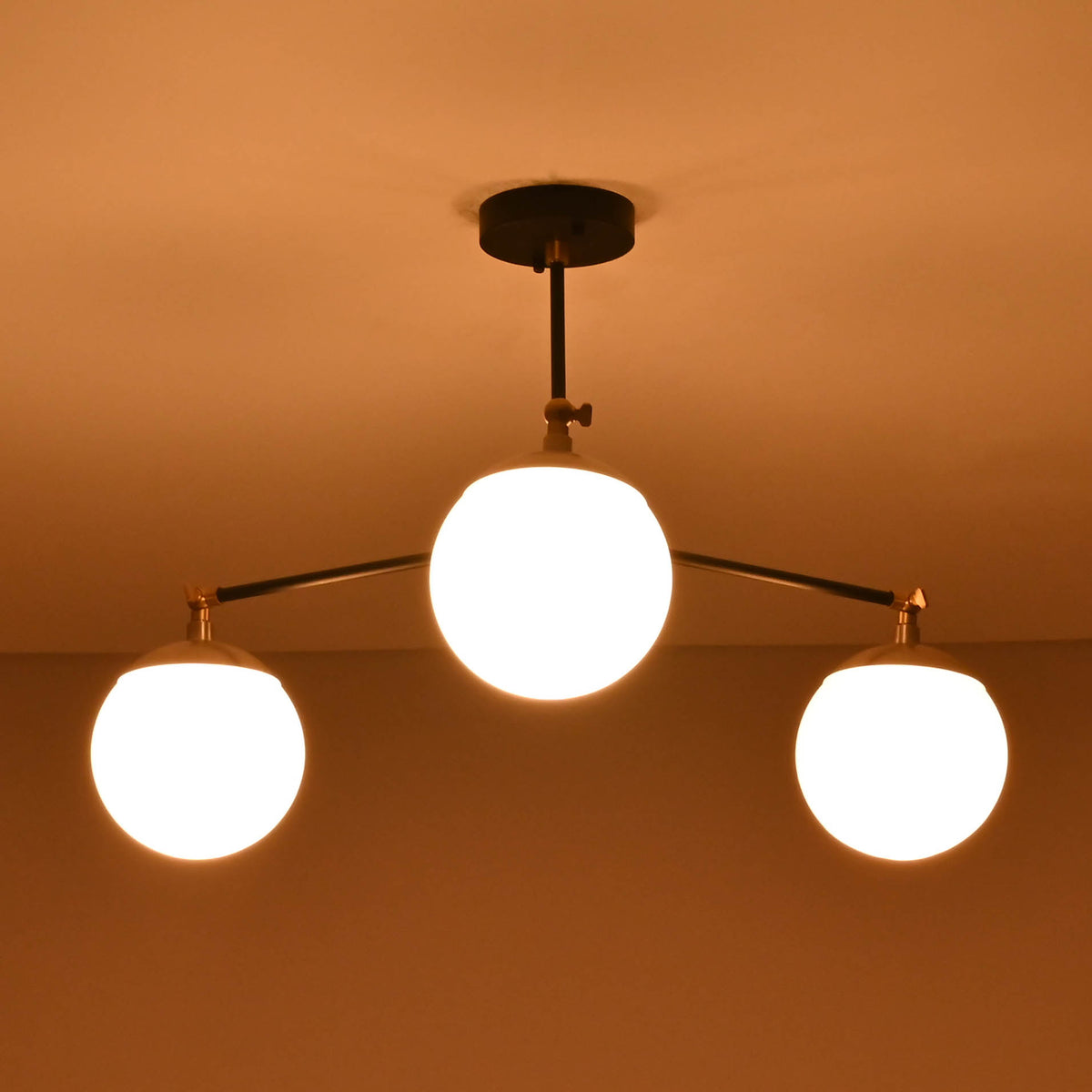 Close-up view of brass flushmount chandelier with three glowing glass globes