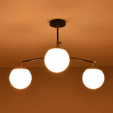 Close-up view of brass flushmount chandelier with three glowing glass globes