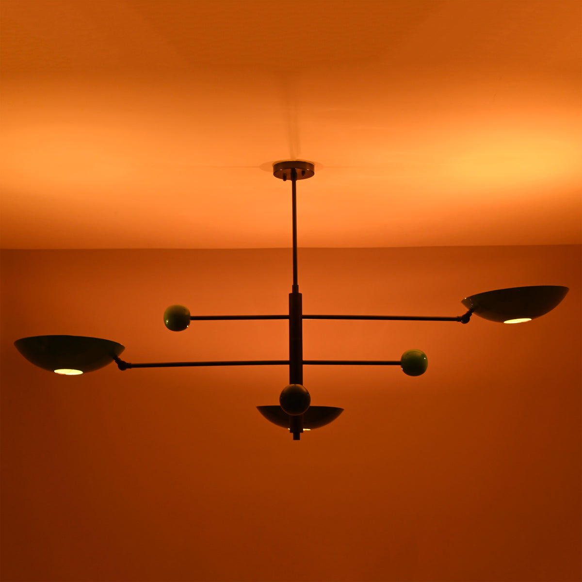 Large Sputnik chandelier illuminated in a dark room, featuring bold modern disc shades and brass detailing