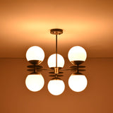 Brass and black chandelier with six opal glass globes glowing warmly against the ceiling