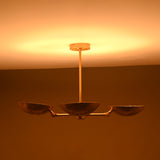 Warm light emitted by concave brass bowls casting golden tones upward to ceiling in dark interior