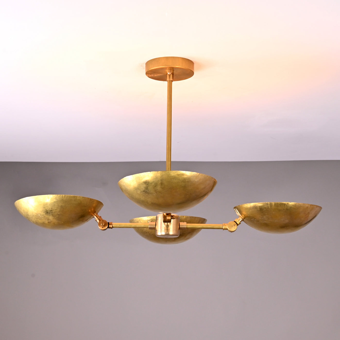 Front angle view of handcrafted solid brass chandelier with four hammered bowl shades and central brass rod suspension.