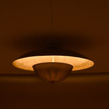 Handcrafted brass disc light with soft inner glow highlighting its smooth circular form in a dimly lit room