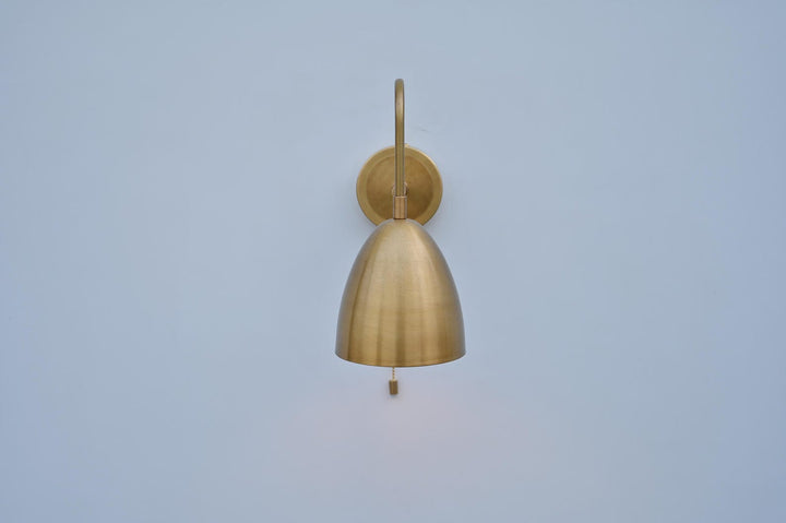 Front view of handcrafted brass dome sconce highlighting its curved dome shape and sleek wall mount in brushed brass finish.