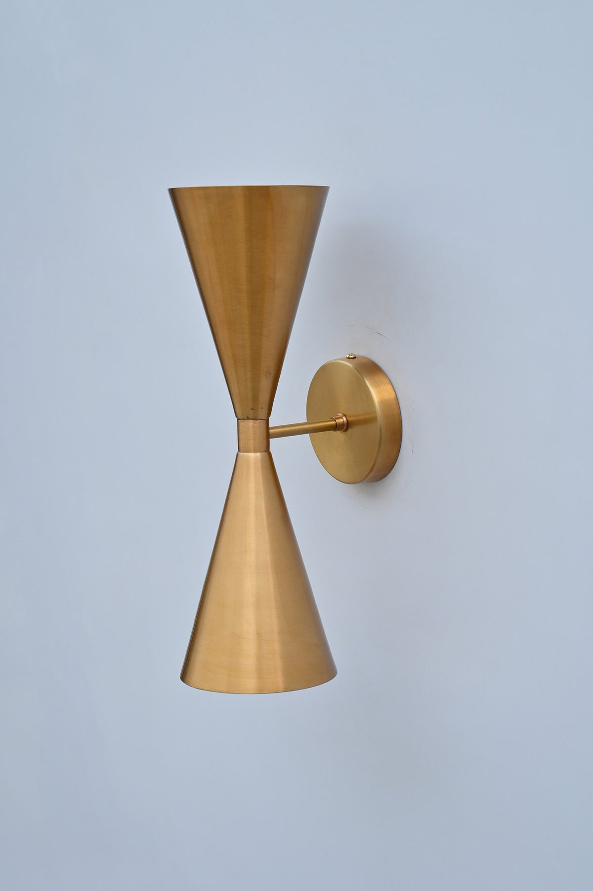 Close-up view of handcrafted brass double cone wall light highlighting premium satin texture and fine metal craftsmanship.