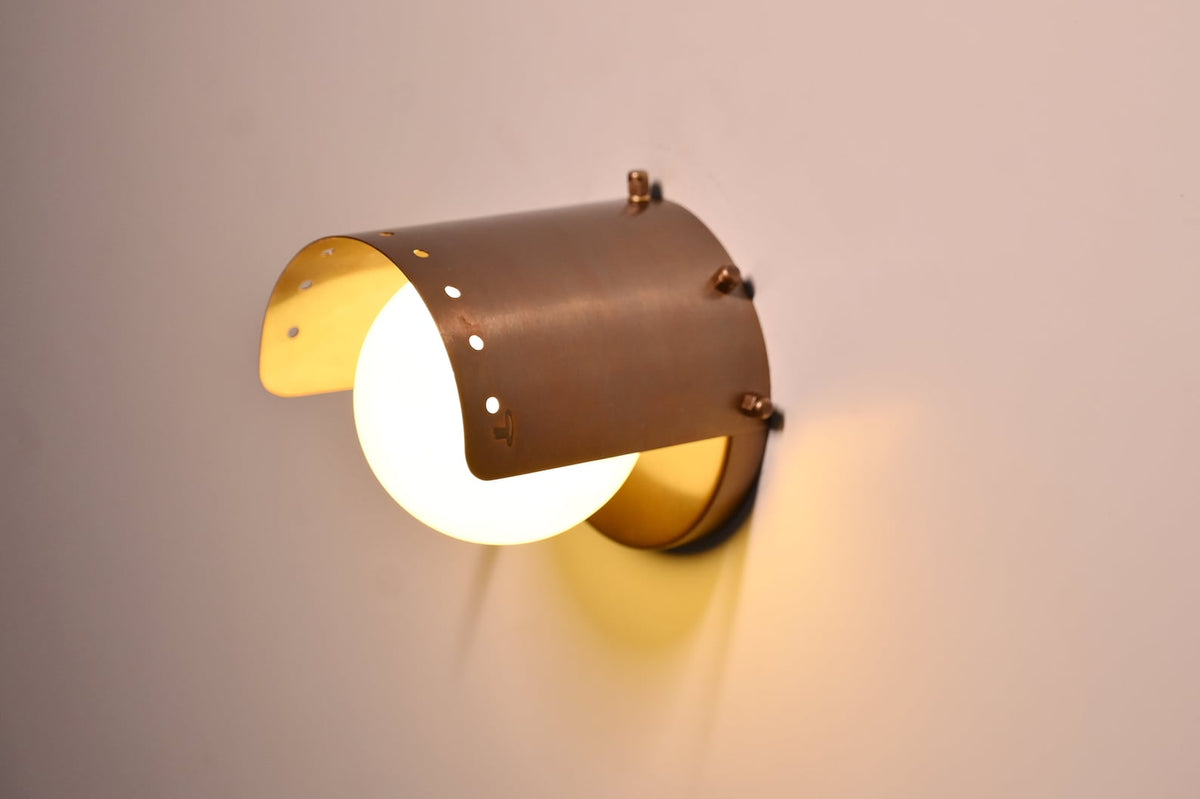 Handcrafted brass wall sconce emitting warm ambient glow, perfect for living rooms and bedrooms