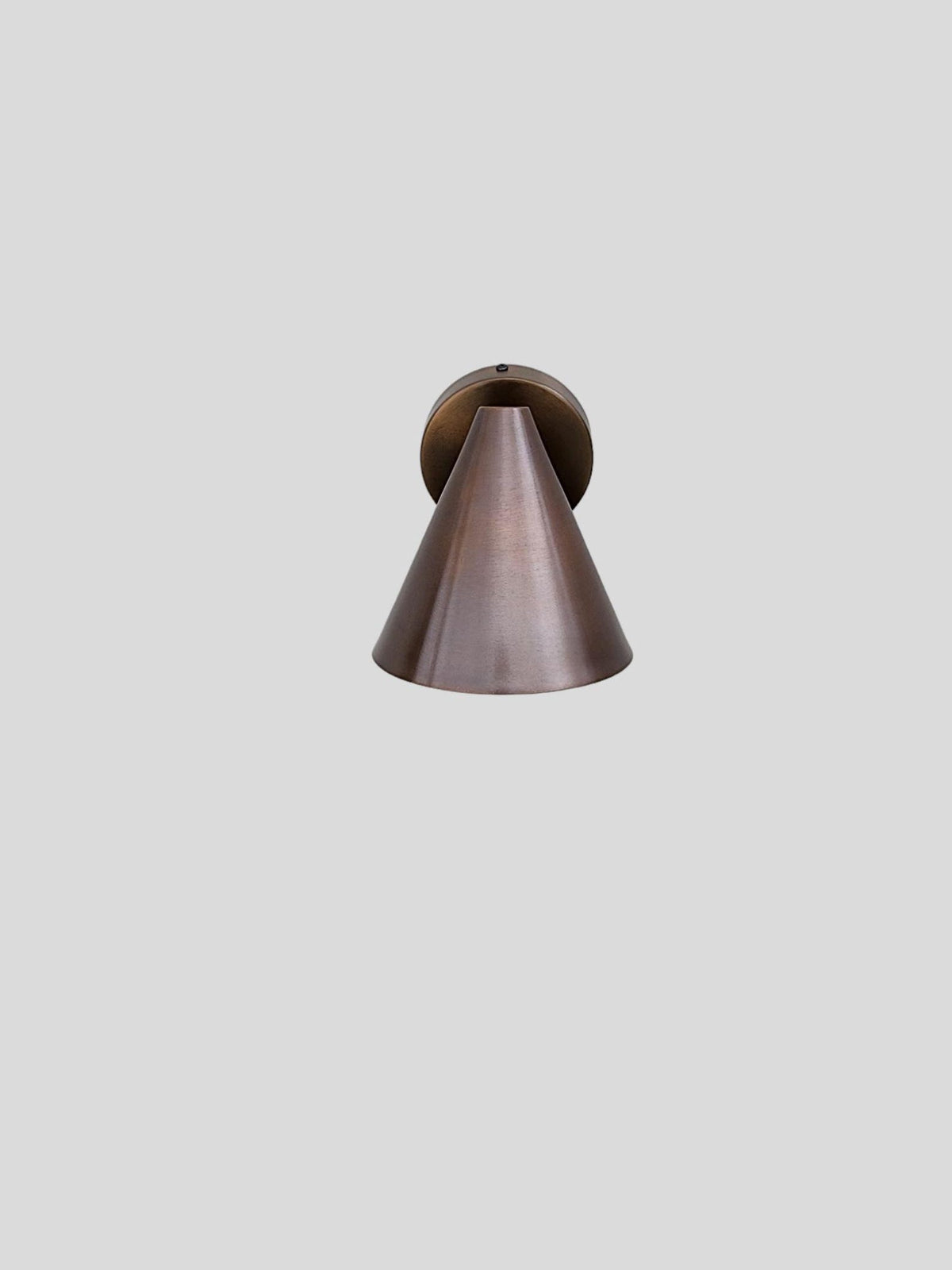Handcrafted minimalist wall sconce in brushed copper finish with elegant cone shape and industrial-inspired design.