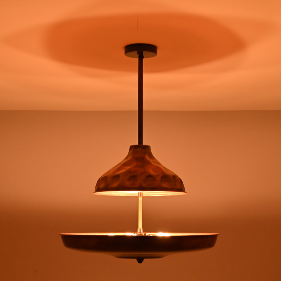 Modern copper disc chandelier with warm indirect lighting and sculptural bowl shade, handcrafted from solid brass