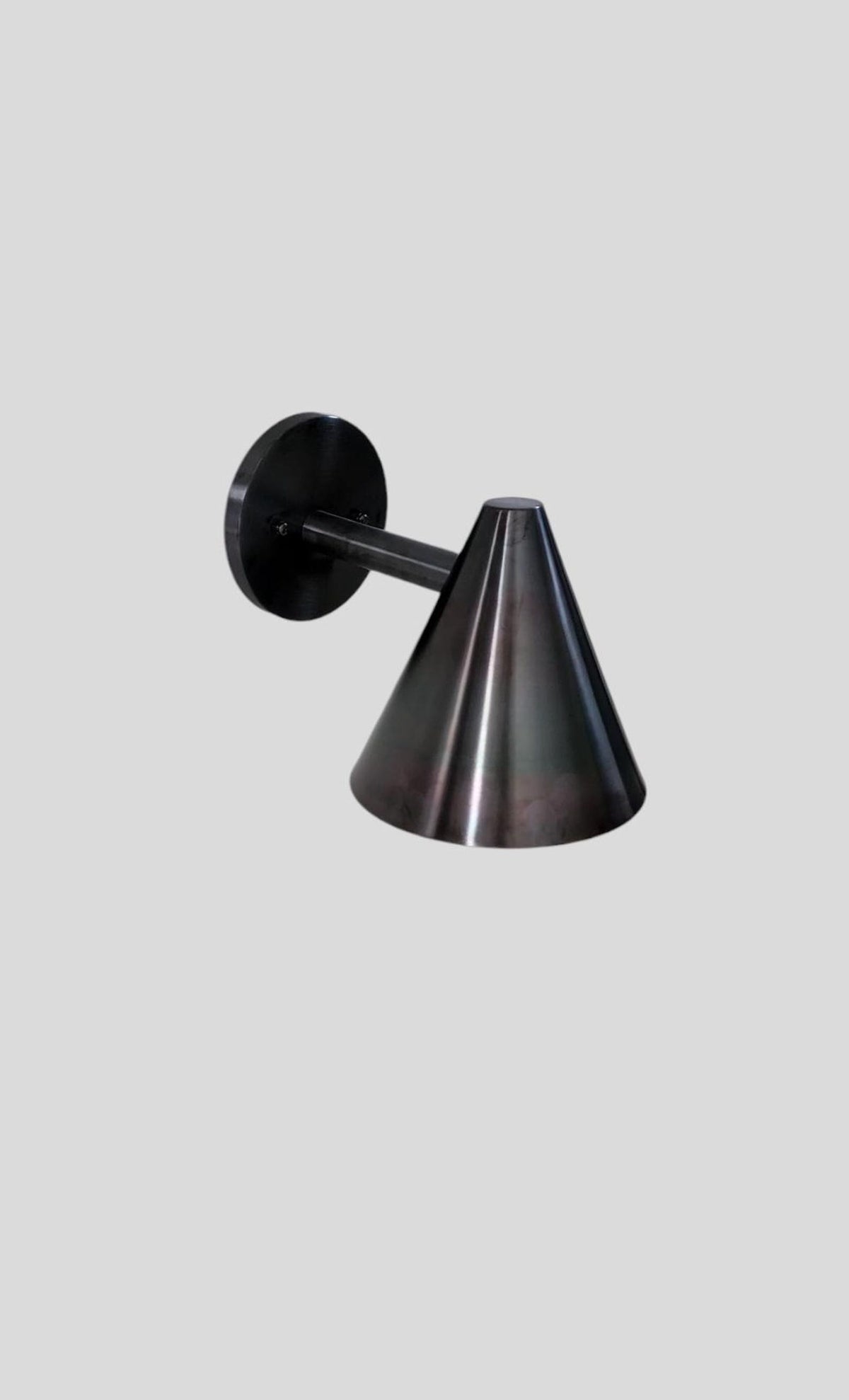 Handcrafted industrial-style wall sconce in blackened brass, featuring clean lines and cone shade for focused ambient light.