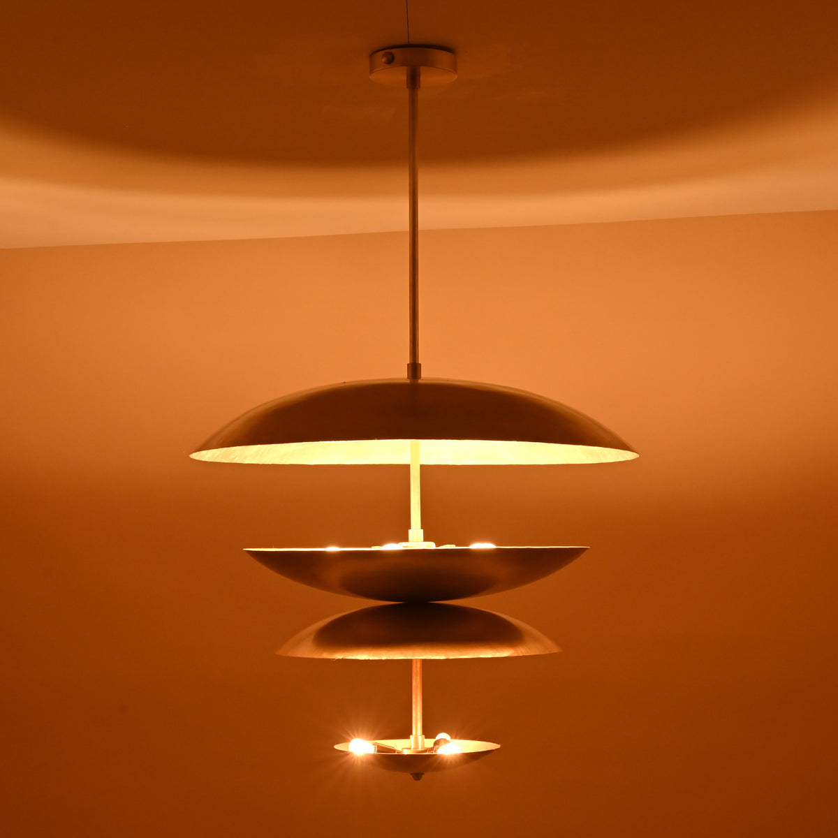 Handmade layered brass pendant with 8-light arrangement casting golden radiance