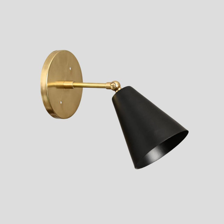 Modern black cone wall sconce with solid brass base, handmade industrial lighting fixture, side angle view.