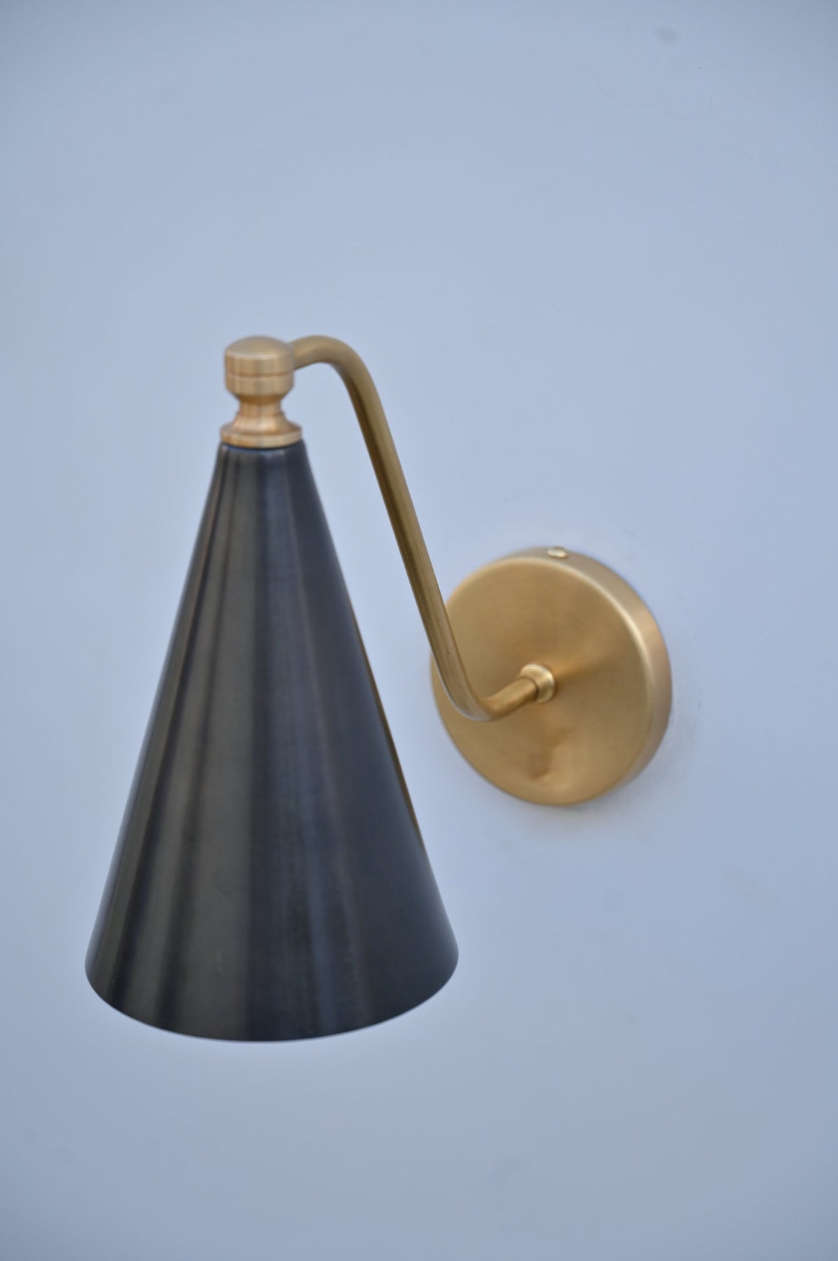 Handmade blackened brass wall light with golden brass arm, designed by Brass Leaf Studio for modern interiors.