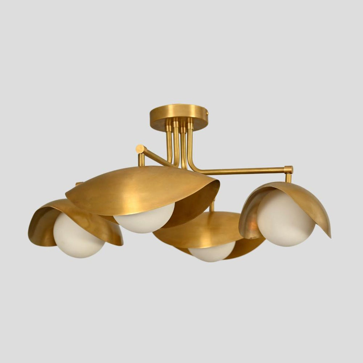 Side perspective of handmade brass flushmount chandelier featuring sculpted bowl shades with white globes for warm ambient lighting