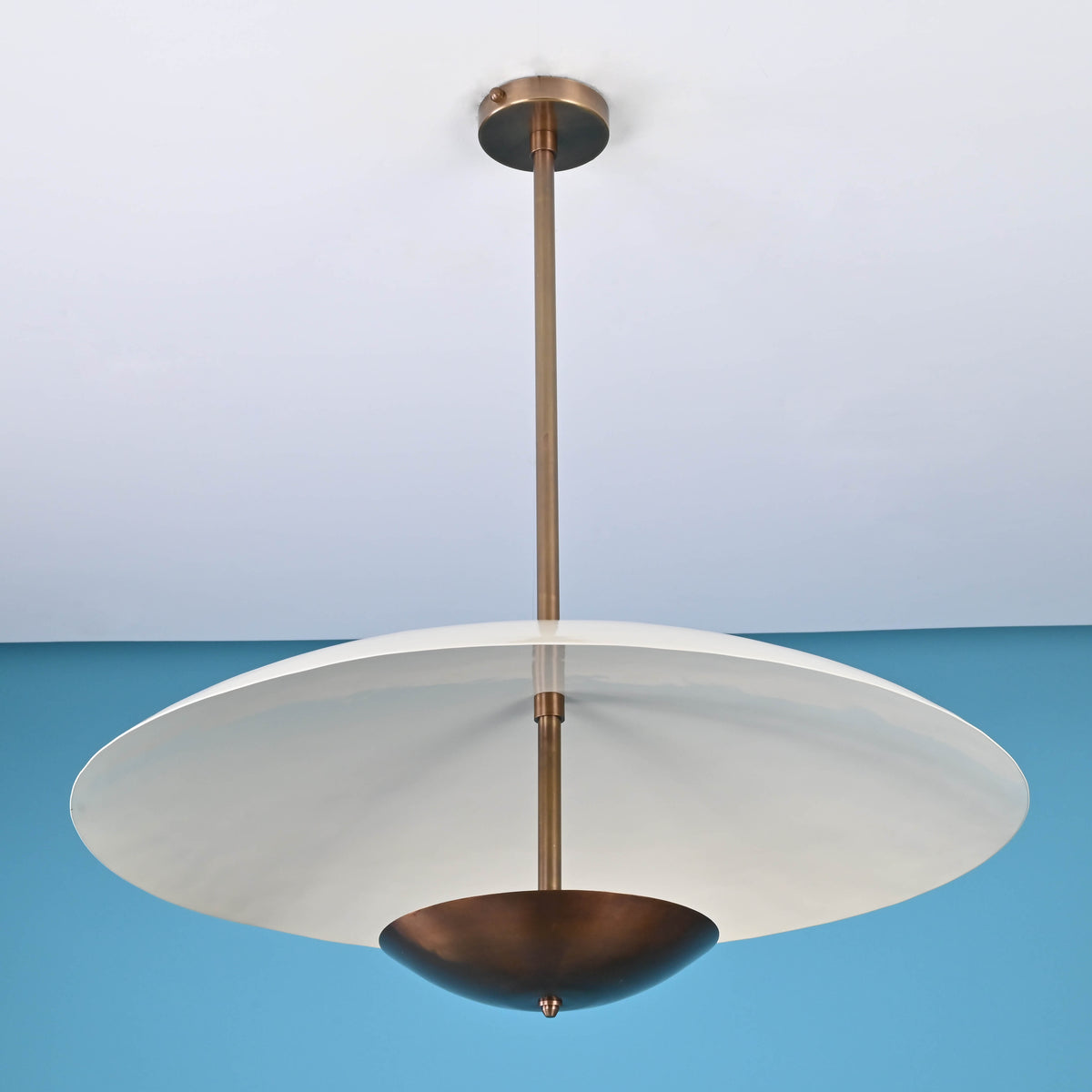 Handmade brass pendant light with sculptural design, suspended rod, and lacquered dome finish, crafted by Brass Leaf Studio for modern interiors.