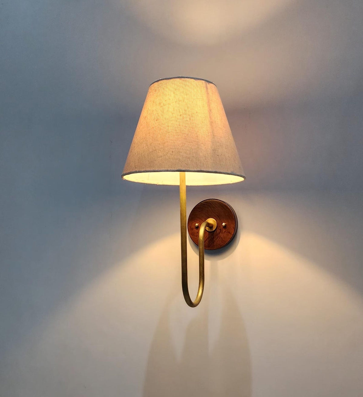 Side view of handmade brass wall light featuring a warm fabric shade and solid brass construction for ambient lighting.