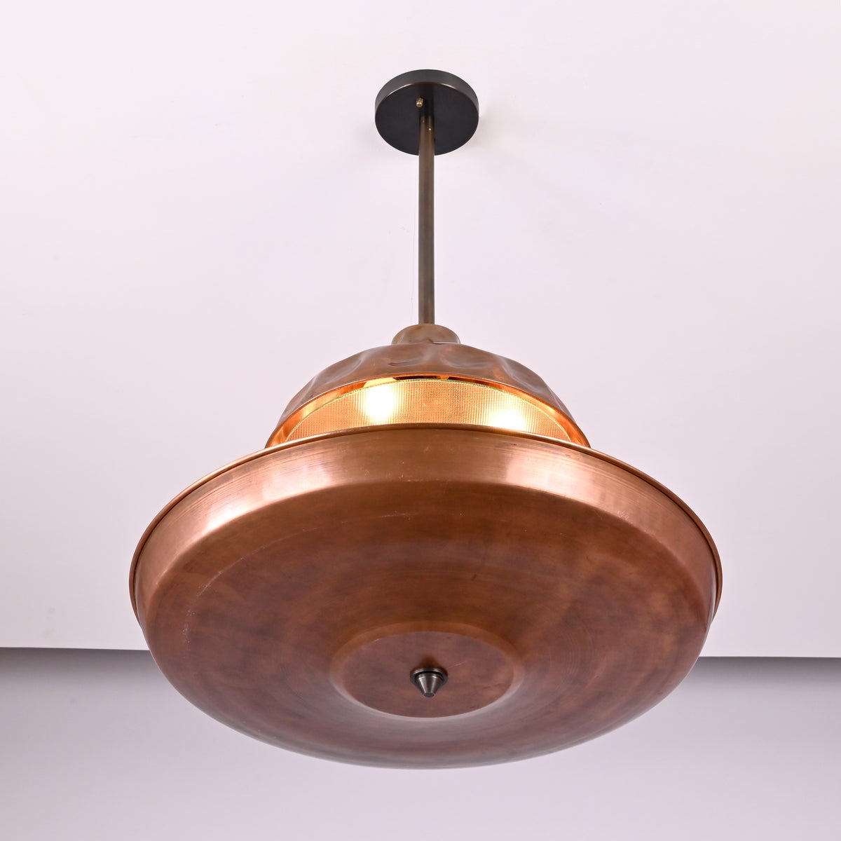 Close-up of handcrafted copper chandelier showing hammered texture, bowl-shaped shade, and refined brass detailing