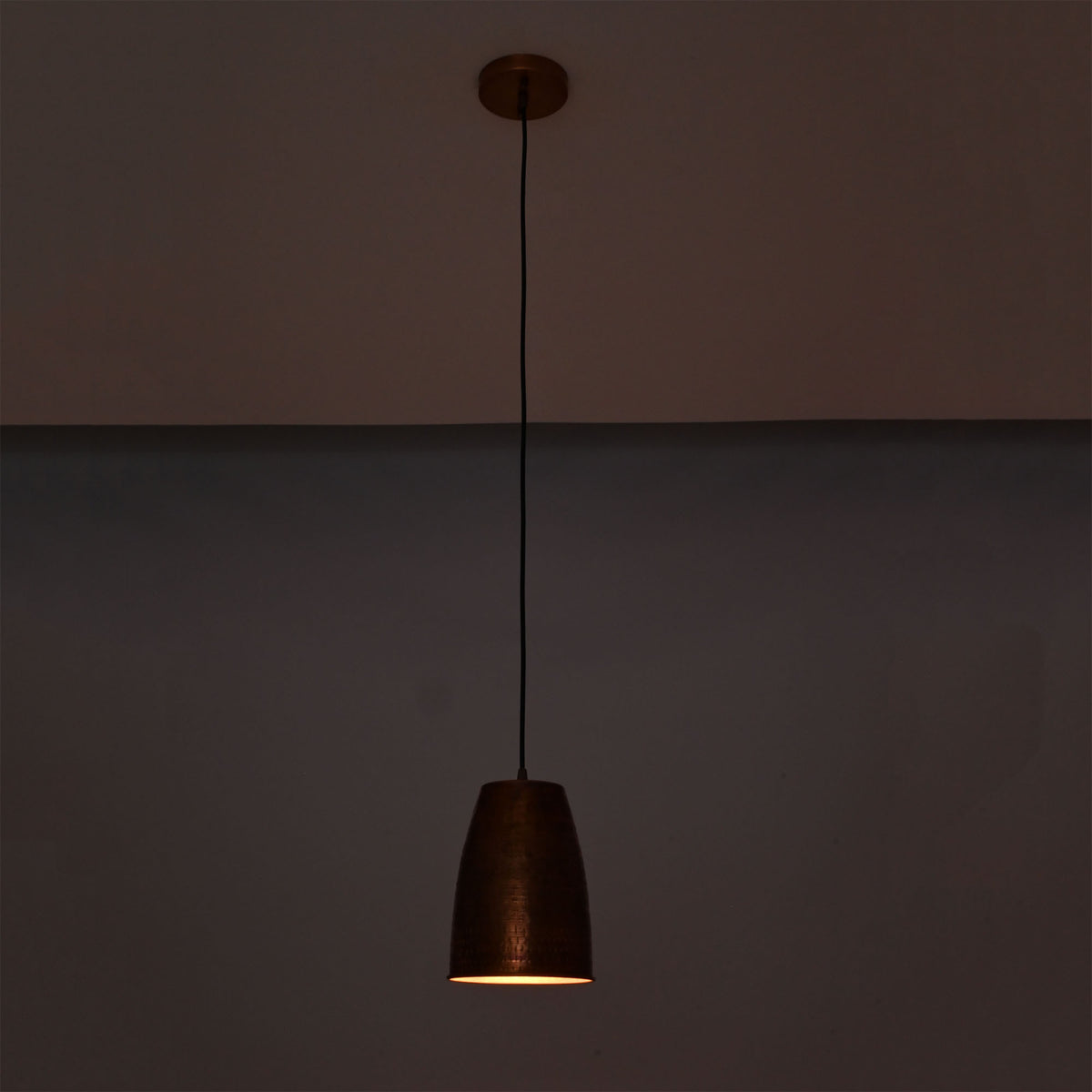 Hudson Hammered Copper Bell Pendant Light illuminated with warm downward lighting for ambient interiors.
