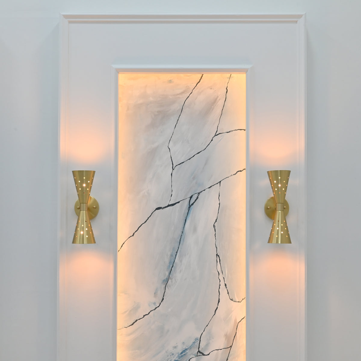 Illuminated Ibiza brushed brass wall sconce creating warm up and down light with glowing perforated details