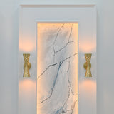 Illuminated Ibiza brushed brass wall sconce creating warm up and down light with glowing perforated details