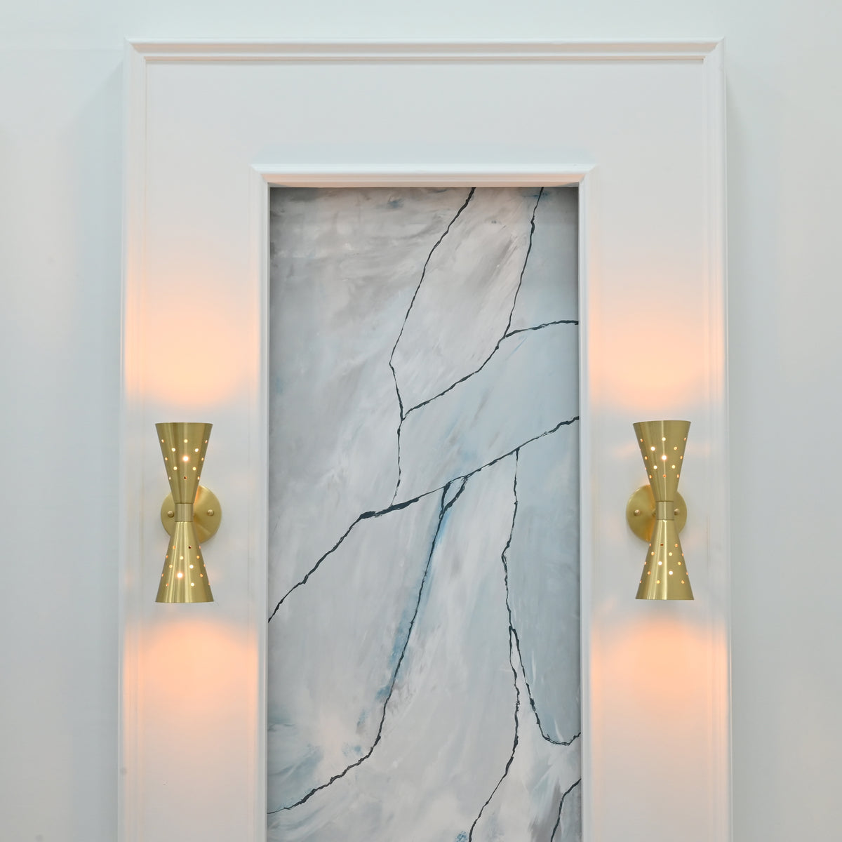 Close view of Ibiza wall sconce showing brushed brass surface, perforated shades and sculptural double cone form