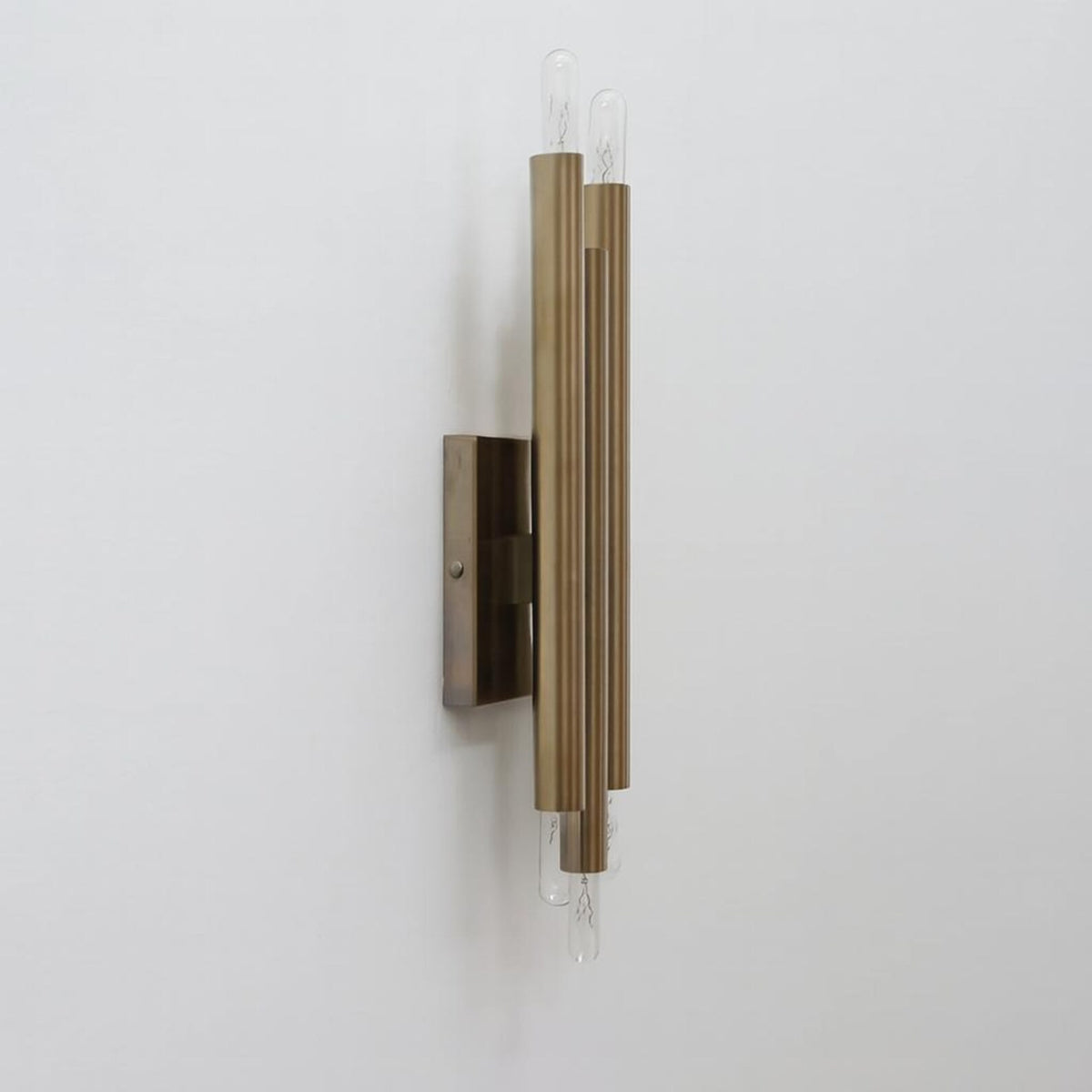 Industrial solid brass tube wall light with vertical cylinder design and exposed bulbs side angle view