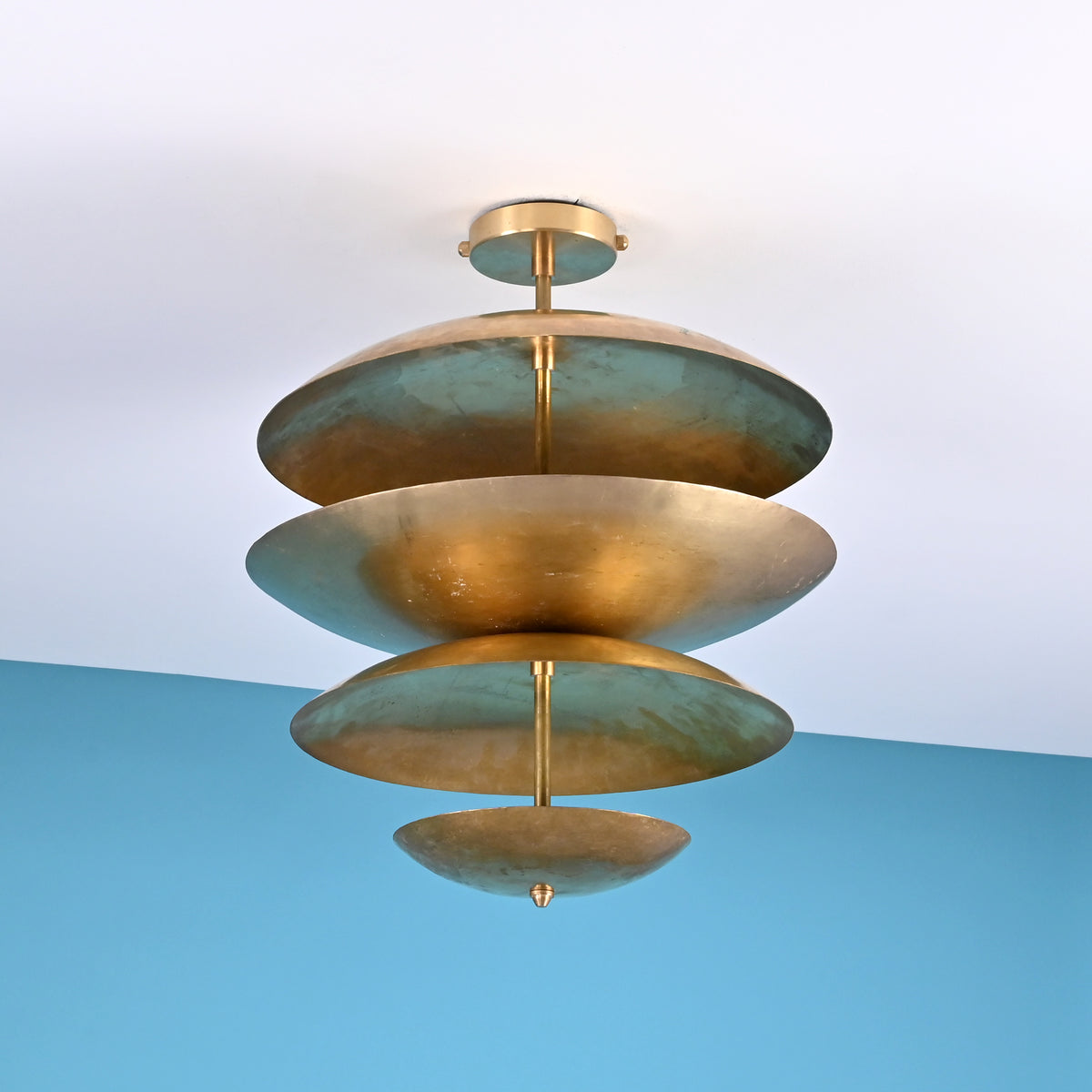 Angled view of modern layered brass ceiling light with sculpted bowl shades creating soft ambient indirect lighting.