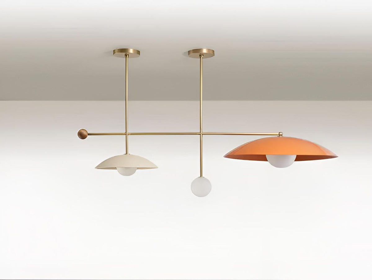 Linear brass ceiling chandelier featuring asymmetrical disc shades and glass globes, blending modern design with warm ambient lighting.