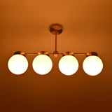 Night view of handcrafted brass linear chandelier with opal glass globes emitting warm, diffused lighting.
