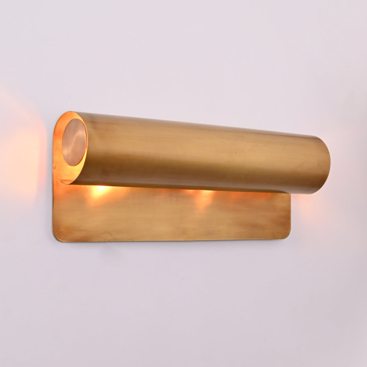 Closeup of Brass Patina linear wall sconce showing cylindrical shield and warm inner lighting