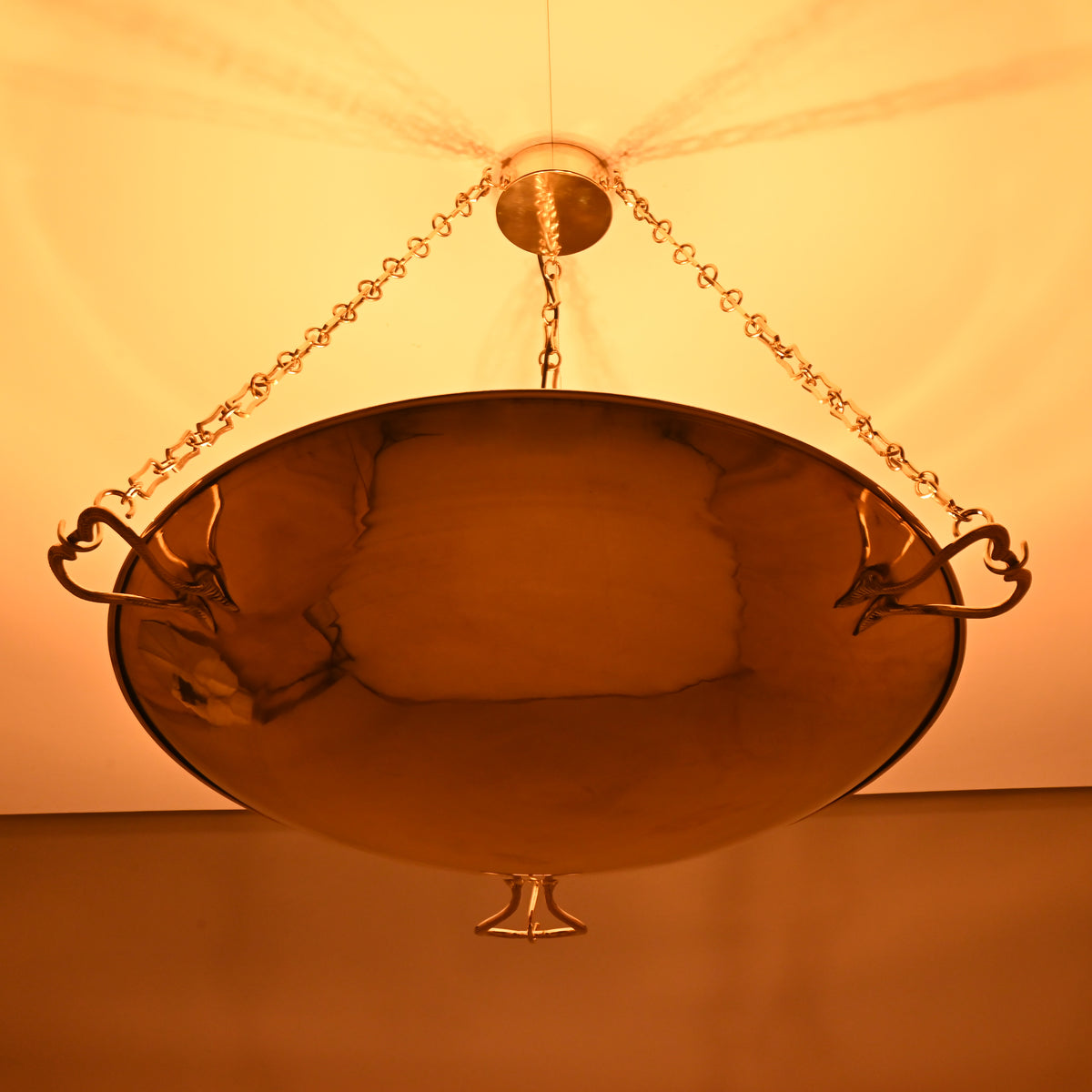 Luxury brass bowl chandelier with decorative hook details glowing warmly in night lighting