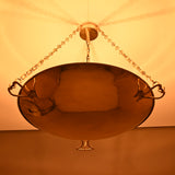 Luxury brass bowl chandelier with decorative hook details glowing warmly in night lighting