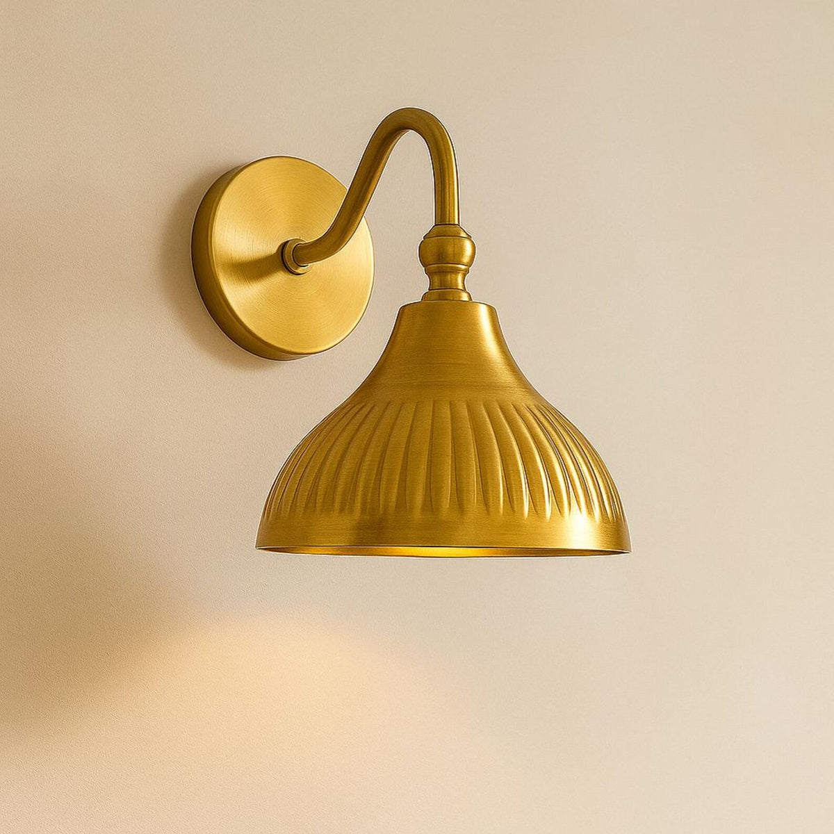 Luxury brushed brass wall lamp with curved arm and fluted shade mounted on wooden panel wall.