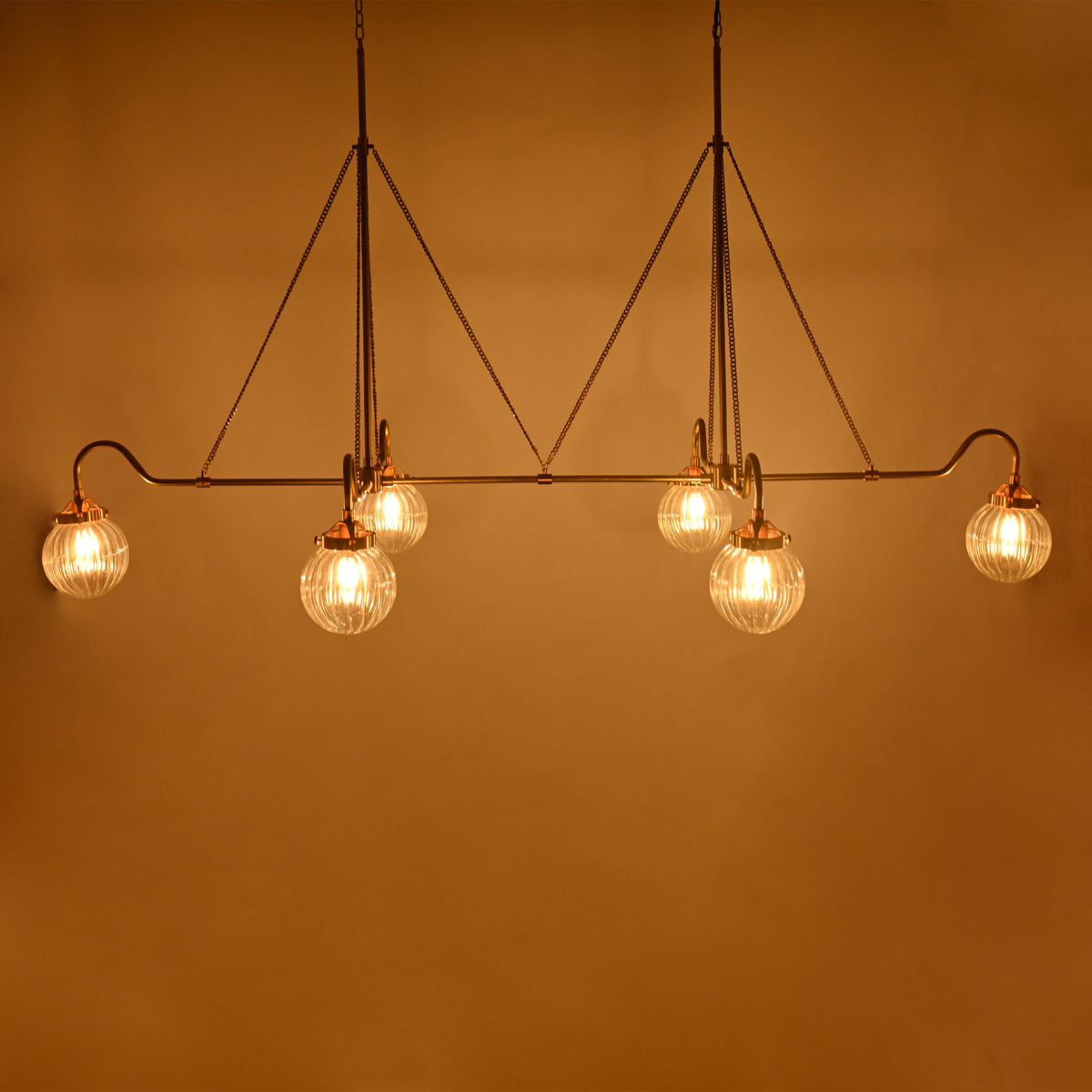 Luxury linear glass globe chandelier installed in a hotel-style lounge with warm lighting and elegant interior décor
