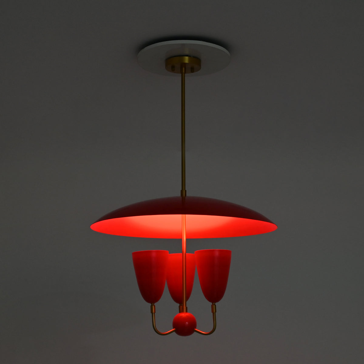 Three light red dome chandelier in full brass construction with enamel painted shades and decorative center ball
