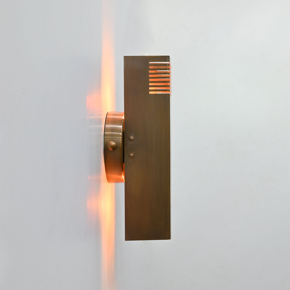 Marbella brass wall sconce front view featuring a clean rectangular body, round backplate, and brass patina finish
