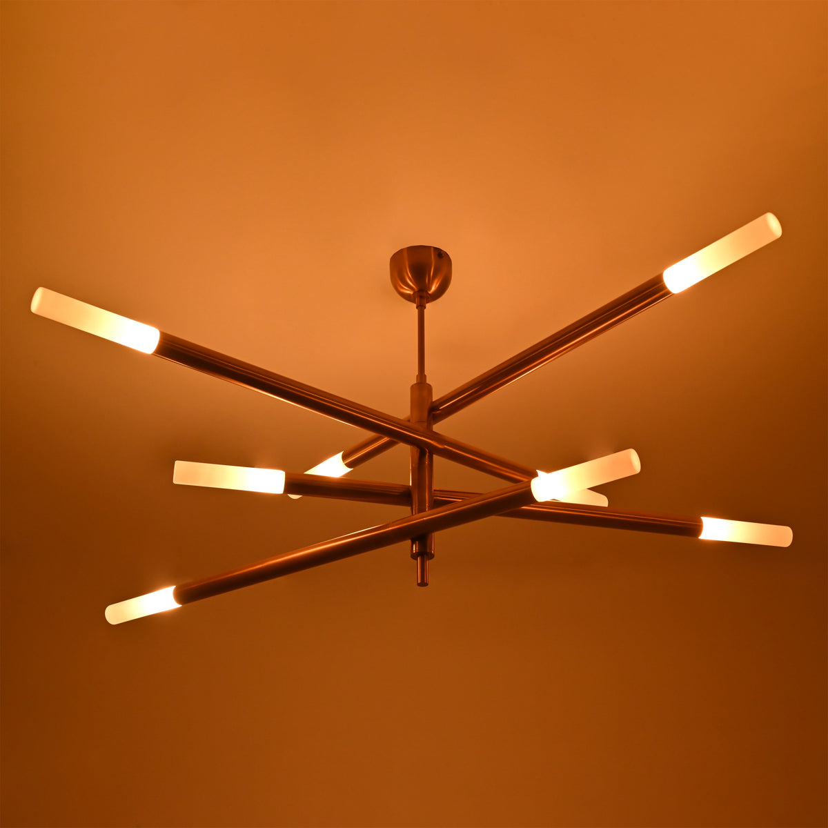 Statement brass chandelier with geometric tubular form, warm raw brass finish and multi-directional lighting