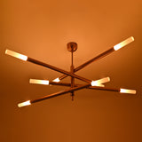 Statement brass chandelier with geometric tubular form, warm raw brass finish and multi-directional lighting