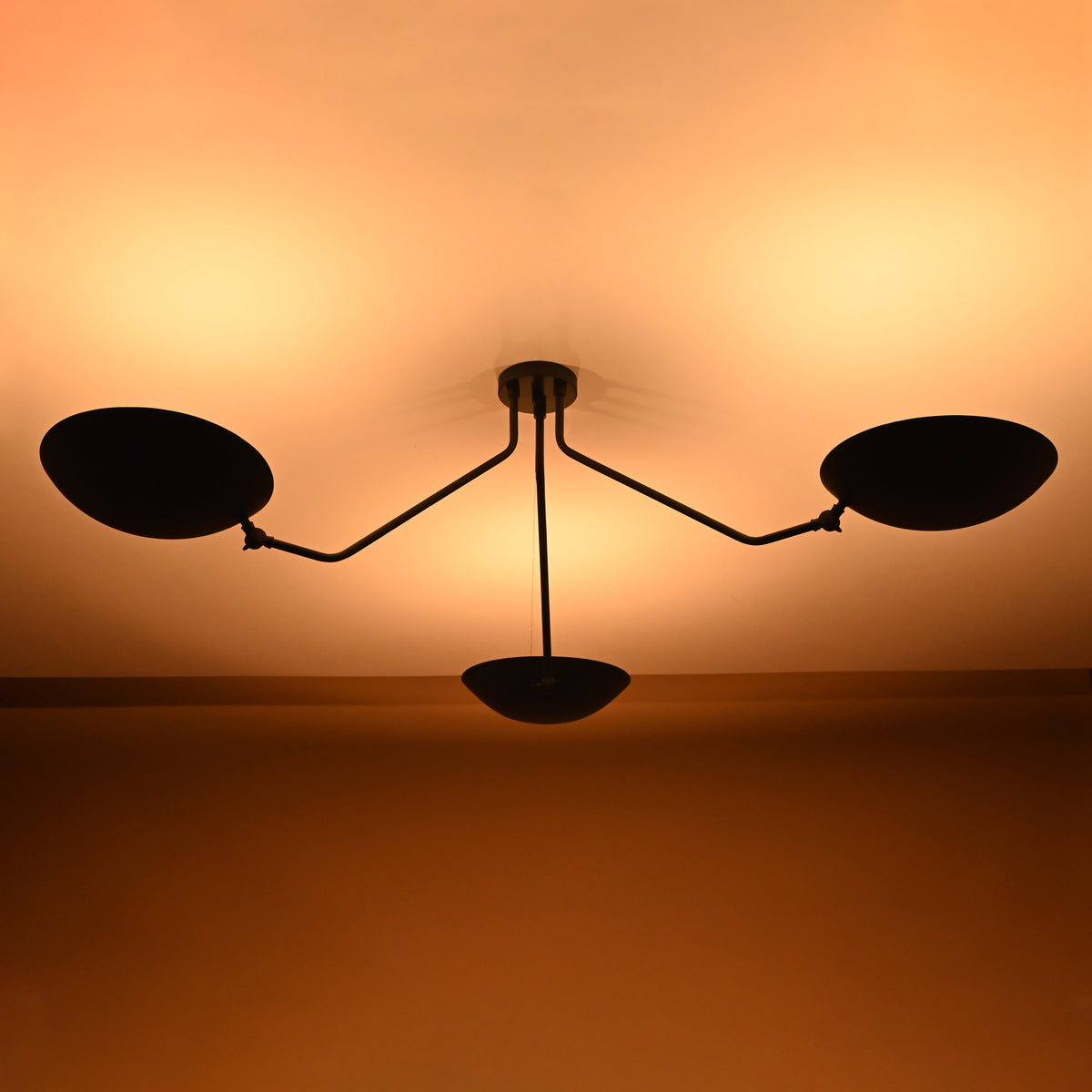 Nighttime glow of minimalist matte black brass chandelier with indirect ambient lighting effect