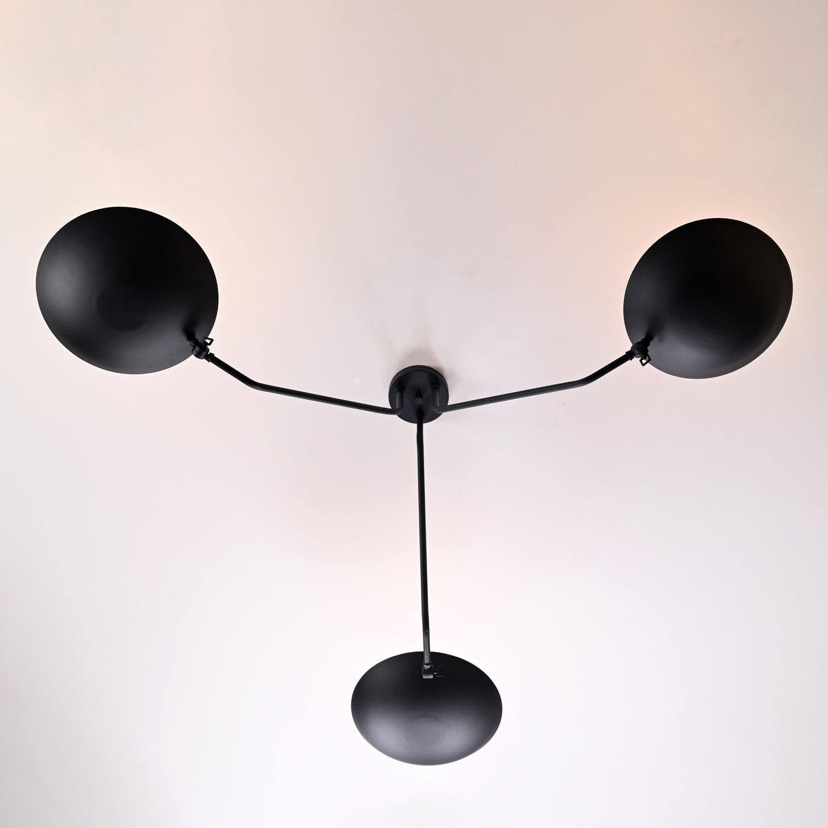 Overhead view of handcrafted matte black brass ceiling light with symmetrical three-arm layout by Brass Leaf Studio