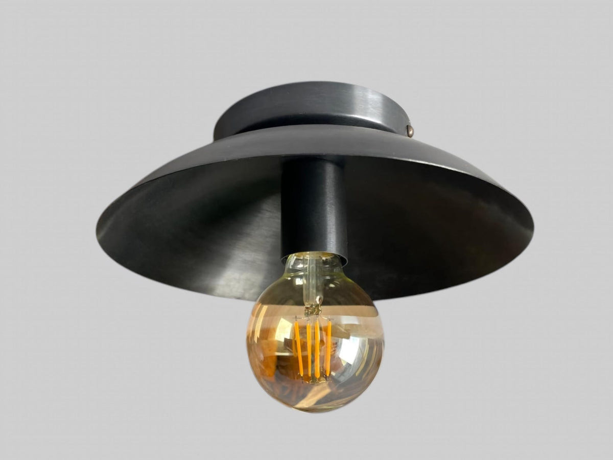 Bottom angle of matte black brass ceiling light with curved dome shade and exposed filament bulb for modern industrial interiors.