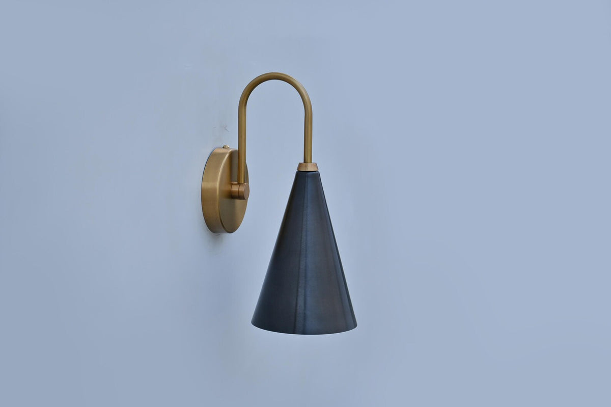 Side angle of matte black and brushed brass wall sconce, showing elegant curved arm and round base design