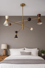 Mid-century modern 6-light diabolo brass chandelier installed above bed with sculptural cone shades and balanced arm design
