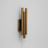 Mid century modern brass 6 light wall sconce featuring vertical cylindrical tubes and minimalist rectangular backplate