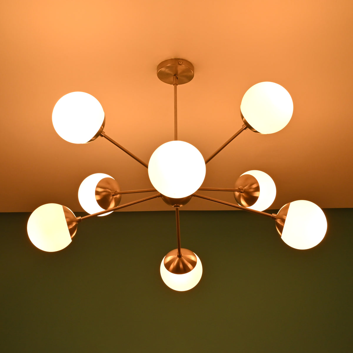 Mid century brass chandelier casting soft ceiling glow with opal glass globe shades