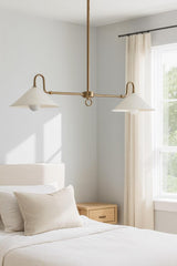 Mid-century modern 2-light brass cone chandelier installed above a bed creating soft ambient bedroom lighting