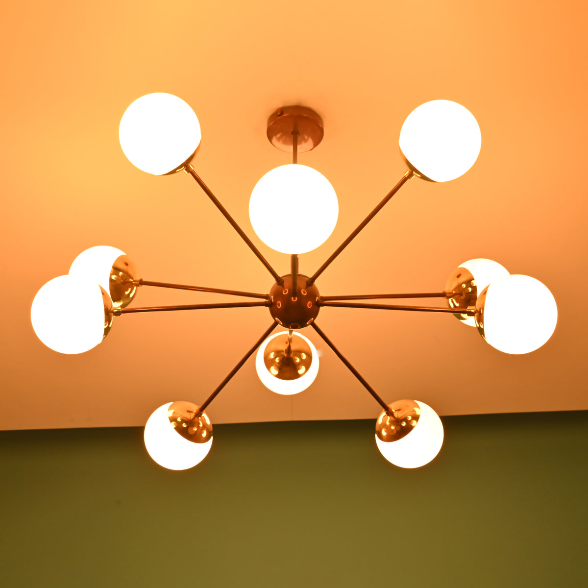 Mid century modern brass globe chandelier casting soft, warm light for elegant residential and hospitality interiors.