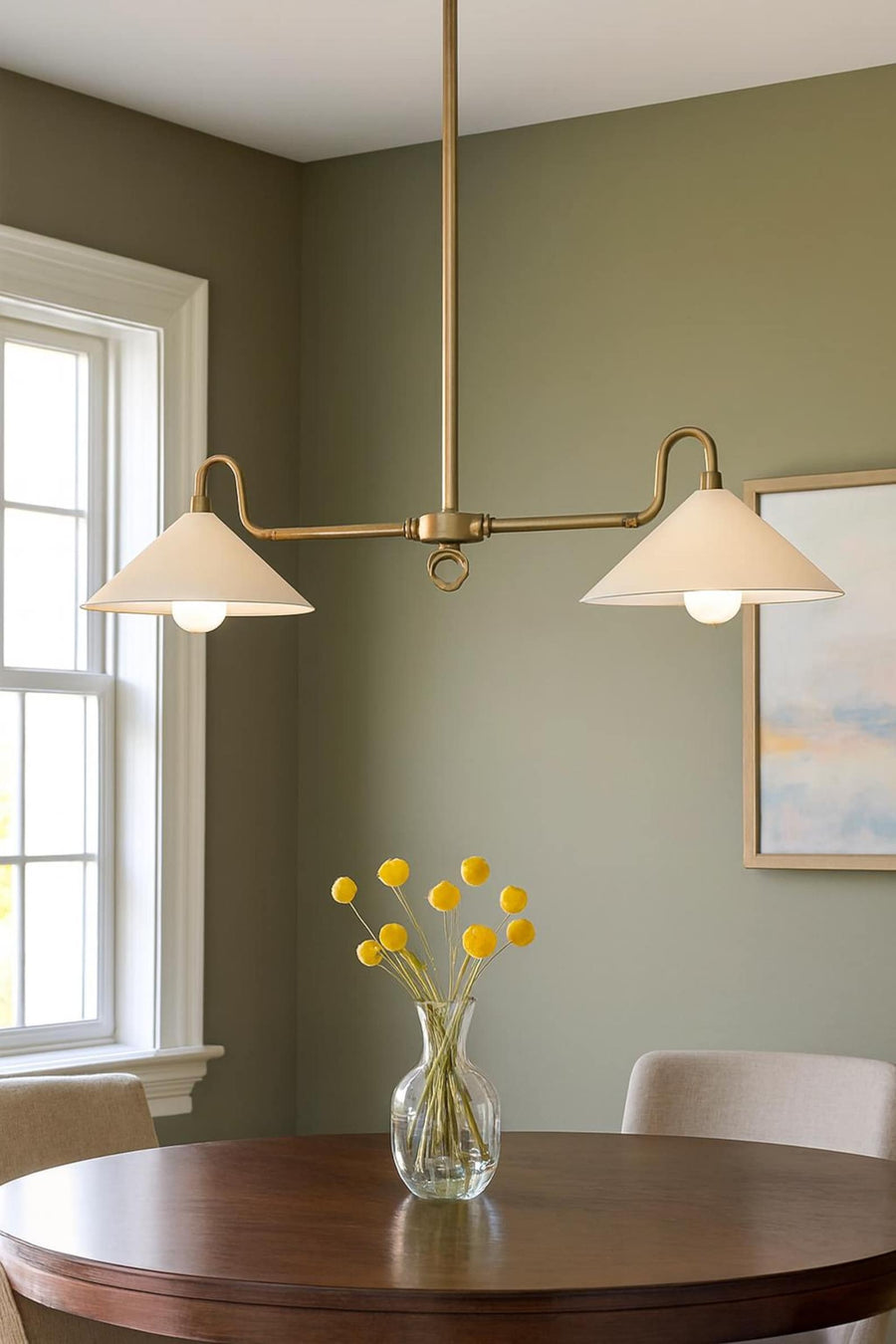 Mid-century modern 2-light cone chandelier in solid brass hanging above a dining table with warm ambient lighting
