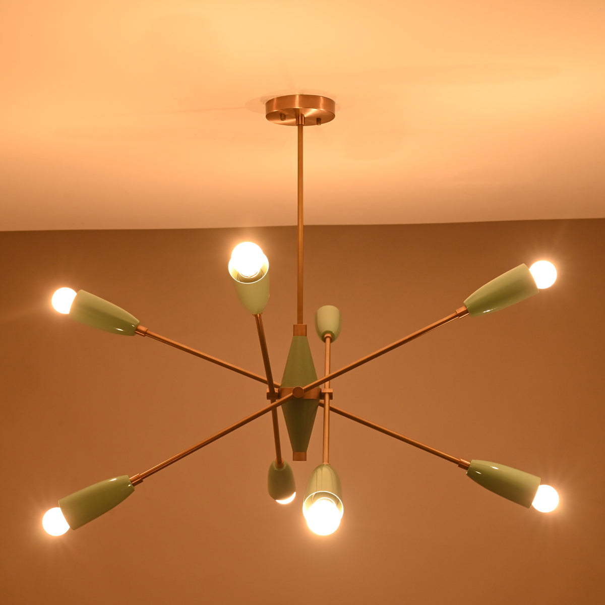 Mid-century modern Sputnik chandelier with 8 illuminated bulbs in a warm-lit room, brass frame and teal shades