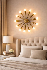 Mid-century starburst brass wall light installed above a bed, creating warm ambient lighting with a sculptural 12-light brass design.