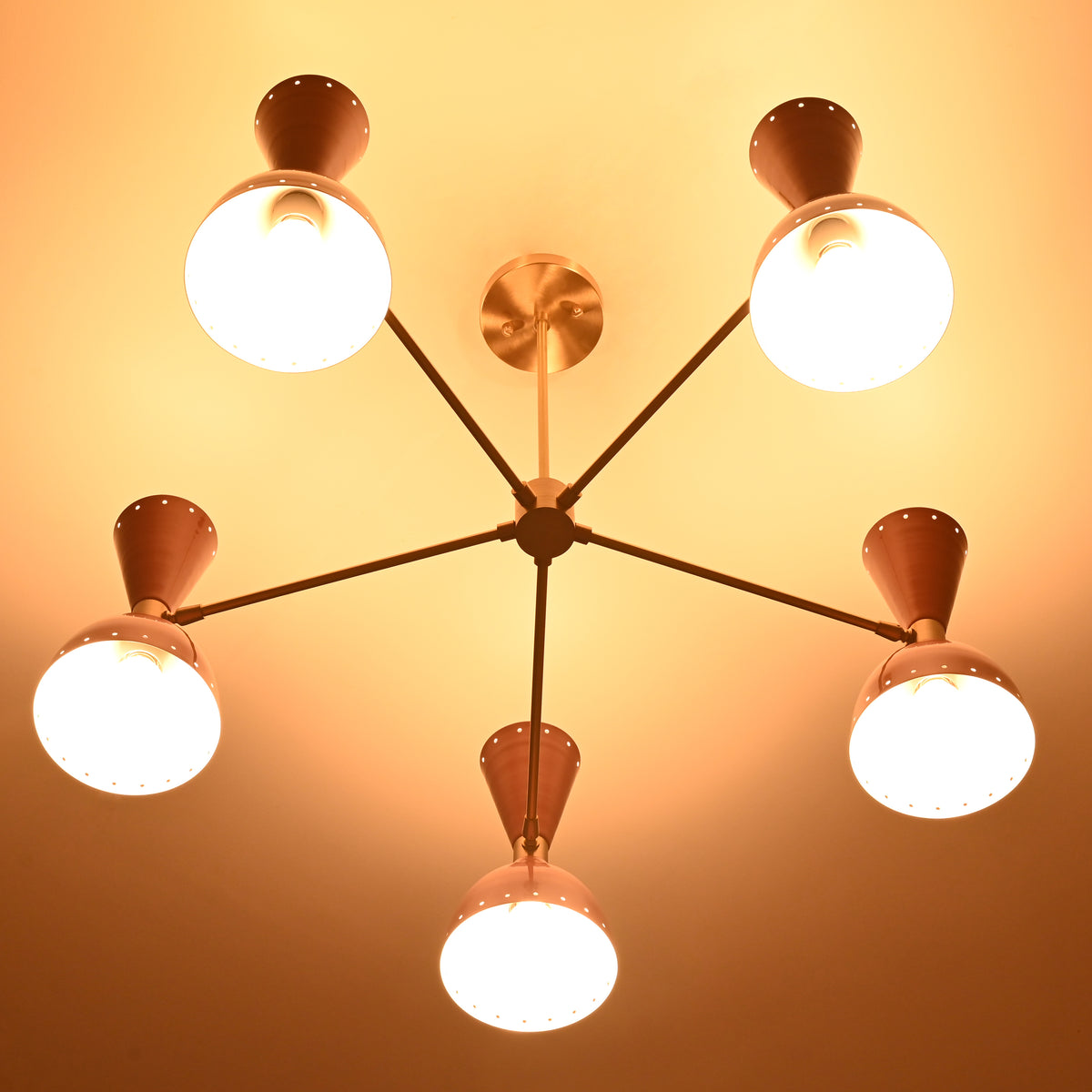Mid-century style peach and brass ceiling chandelier beautifully lit with warm bulbs